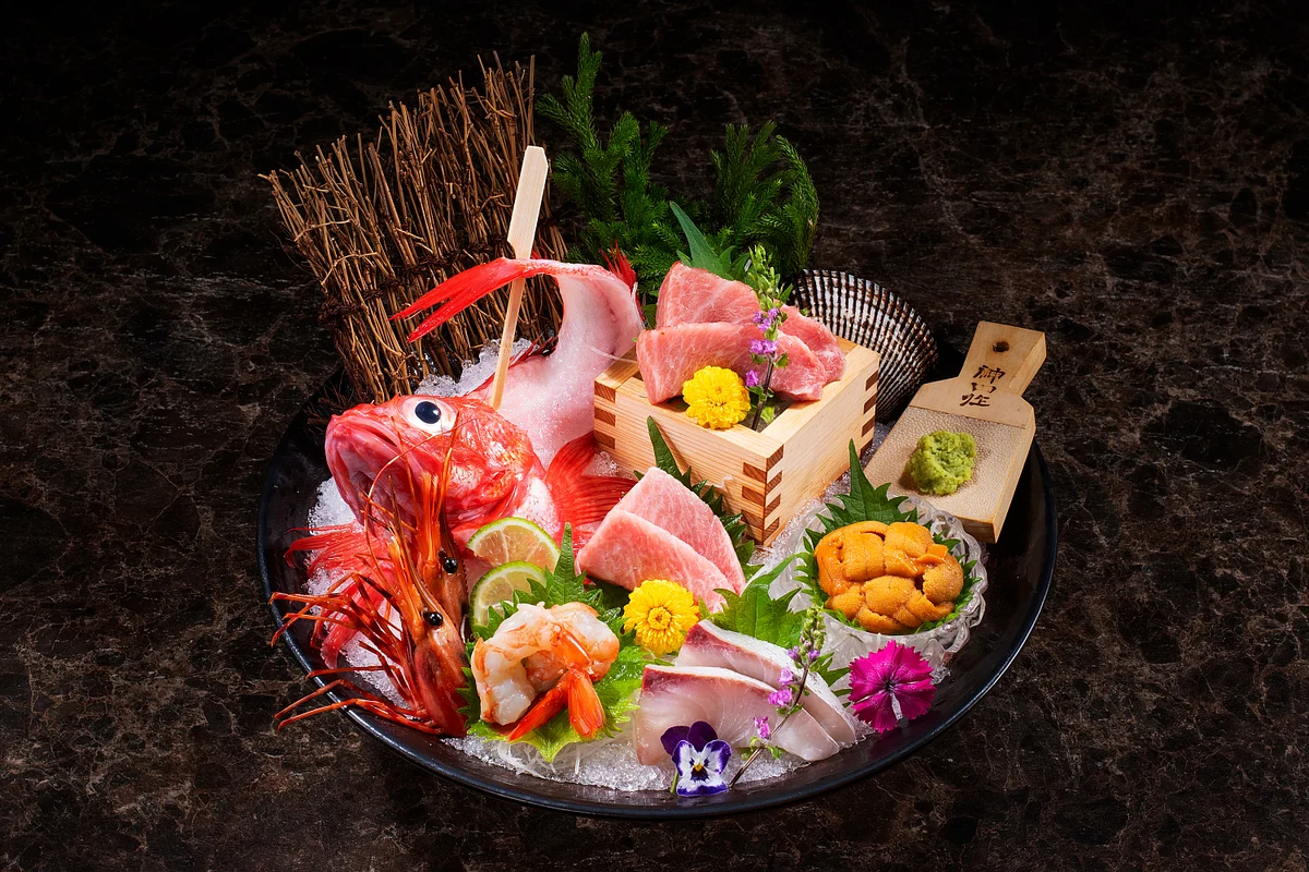 Assorted sashimi and seafood platter with prawns, citrus, flowers, and garnishes