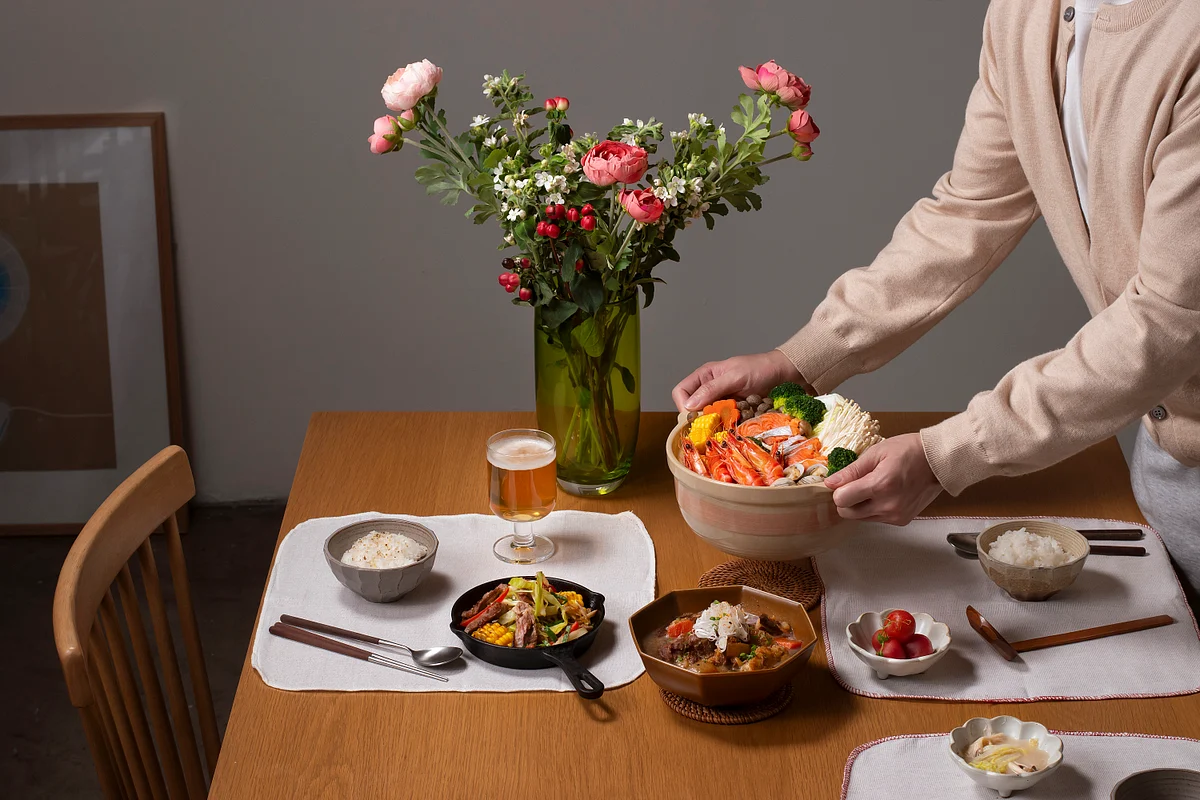 Person serving a colorful salad at a dining table with multiple dishes